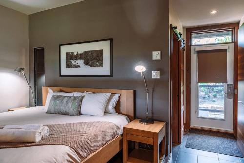 a bedroom with a bed and a lamp on a table at Lakefront and Mountain View - Resort Loft in Lac-Superieur