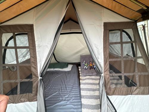 a tent with two windows and a bed in it at Mầm Farmstay And Camping in Lam Ha