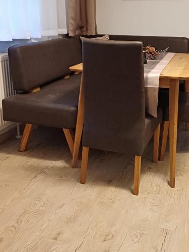 a dining room table with a black chair and a wooden table at Nationalpark Apartments in Apetlon
