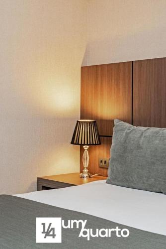 a bedroom with a bed with a lamp on a table at Edifício Praça Osório in Curitiba