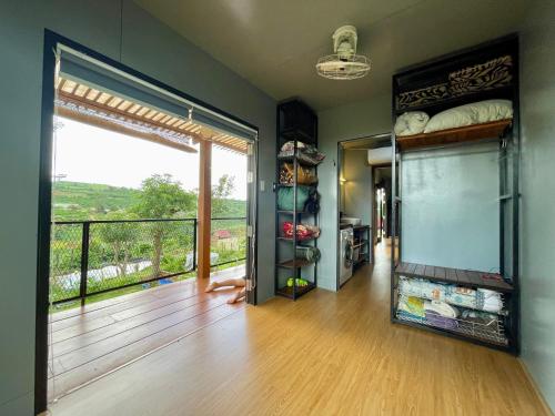 a room with a balcony with a large glass door and a view at Mầm Farmstay And Camping in Lam Ha