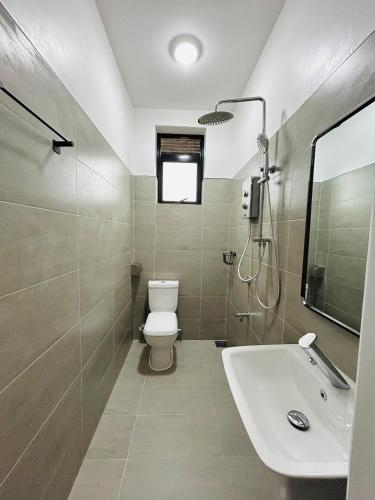 a bathroom with a toilet and a sink at BeHomu Apartments Kampala in Kira