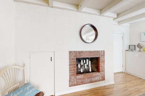a living room with a brick fireplace with a mirror at Sailaway Cabin in Ventura