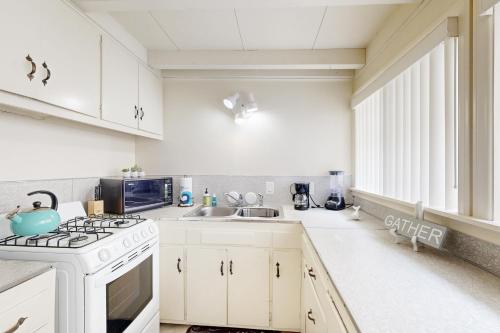 a white kitchen with a stove and a sink at Sailaway Cabin in Ventura
