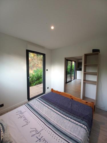 une chambre avec un grand lit avec une grande fenêtre dans l'établissement Tiny house dans l'ouest lyonnais, à Sain-Bel