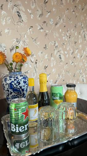 a tray with bottles of alcohol and a vase with flowers at Canal House The Tannery Amsterdam in Amsterdam
