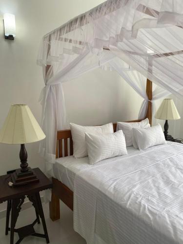 Un dormitorio con una cama blanca con dosel. en Ocean Crest Apartments, en Mihiripenne