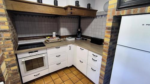 a kitchen with white appliances and a brick wall at Le Doux Rivage, proche de Charleville, jardin et accès à la voie verte in Joigny-sur-Meuse