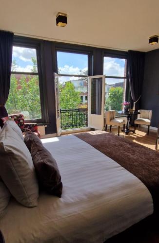 a large bed in a bedroom with large windows at Canal House The Tannery Amsterdam in Amsterdam