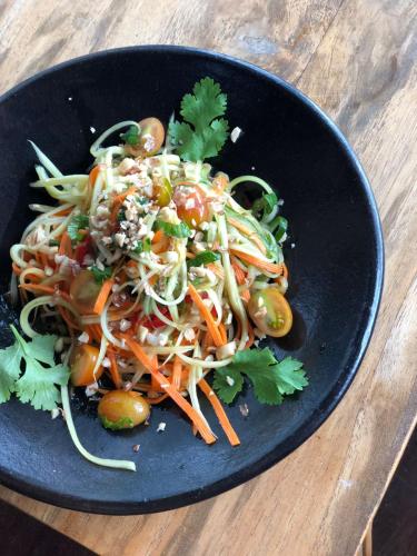 a black plate of food with vegetables and noodles at Villas Bukit Lipah in Amed