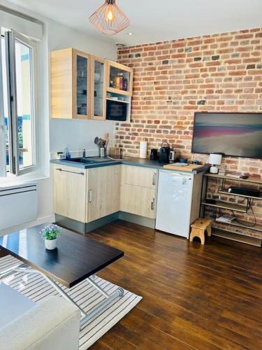 une cuisine avec des placards en bois et un mur en briques dans l'établissement Le Cocon au bord de la mer, à Trouville-sur-Mer