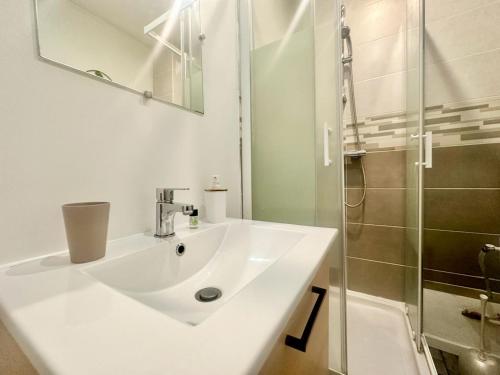 une salle de bain blanche avec un lavabo et une douche dans l'établissement L'Oasis, lumineux et zen, à Limoges