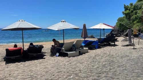 a group of people sitting in chairs on the beach at Villas Bukit Lipah in Amed