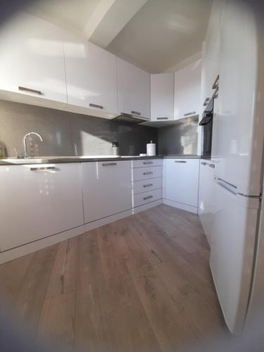 a kitchen with white cabinets and a wooden floor at Apartmani Dojčinović in Vranje