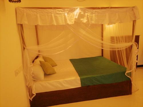 a bedroom with a canopy bed with white curtains at Villa 96 in Unawatuna