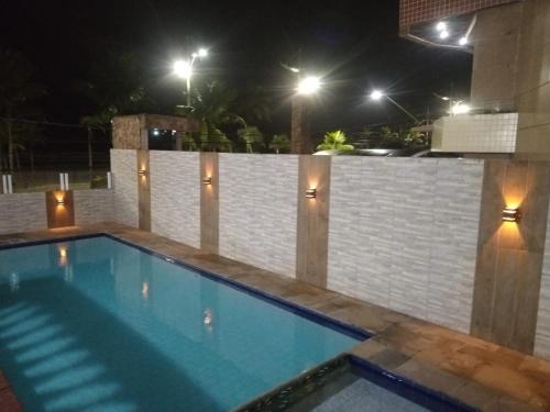 a swimming pool at night with a fence and lights at Apto Frente ao Mar - Vila Tupy in Samaritá