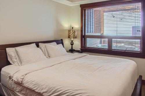 a bedroom with a large white bed with a window at Stonegate Resort Unit C202 in Big White