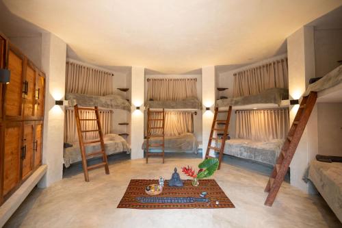 a room with three bunk beds and a table at Leisy's Garden Hostel & Rooms in Santa Bárbara de Samaná