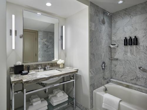 a bathroom with a sink and a tub and a mirror at Hotel AKA Boston Common in Boston