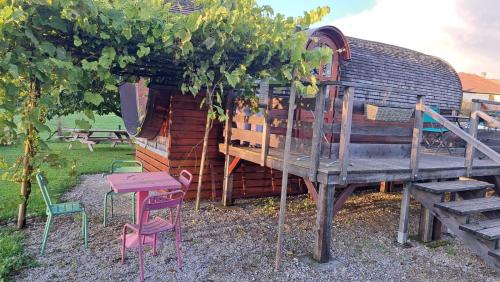 une maison en bois avec des chaises, une table et un arbre dans l'établissement Roulotte viticole, à Loulle