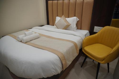two beds in a hotel room with a yellow chair at Hotel Royal Rosette with free Wi-Fi Near New Delhi Railway Station in New Delhi