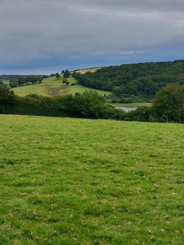 a field of green grass with a lake in the distance at Foxgloves in Brompton Regis