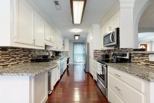 a large kitchen with white cabinets and a wooden floor at Bring Your Pup! Goose Creek Home with Private Pool in Charleston