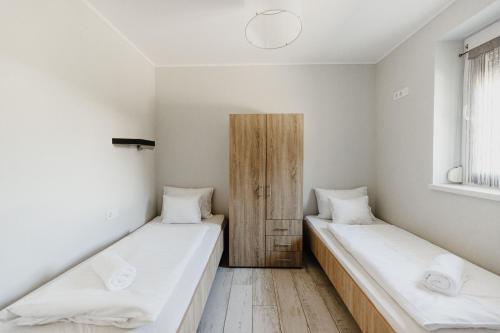 two beds in a room with white walls at Füzeskerti Apartmanház in Békésszentandrás