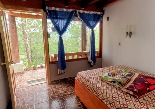 a bedroom with a bed and a window at Laguna Azul Cabaña Lodge Lagunas de Montebello in Santiago