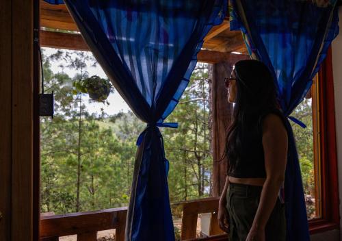 a woman standing in front of a window at Laguna Azul Cabaña Lodge Lagunas de Montebello in Santiago