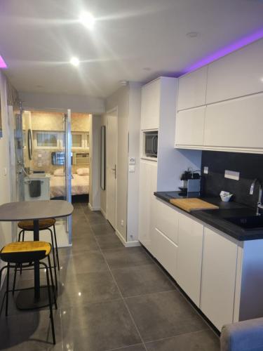 une cuisine avec des armoires blanches et une table et des chaises dans l'établissement Capricia Port Nature 2-Coursives -Vue mer, au Cap d'Agde