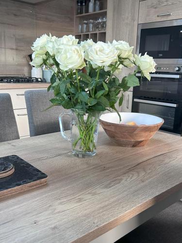 a vase of white roses sitting on a table at Sandy Toes, Padstow in Padstow