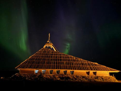 a church with a steeple with the aurora in the sky at Solheimar Eco-Village Guesthouse in Sólheimar