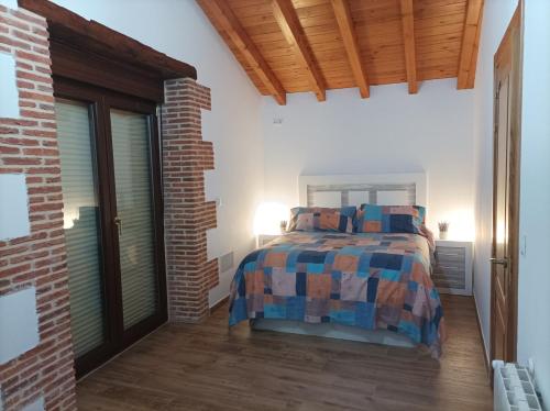 a bedroom with a bed and a brick wall at Casa vacacional Los Enserados in Renedo de Piélagos