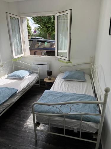 deux lits dans une chambre avec une fenêtre dans l'établissement T3 à Poitiers proche du Futuroscope, à Poitiers