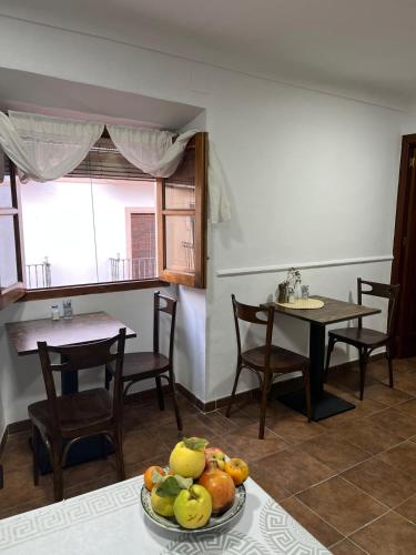Una cocina con una mesa y sillas y un bol de fruta. en Alojamiento La Escalera, en Alhama de Granada
