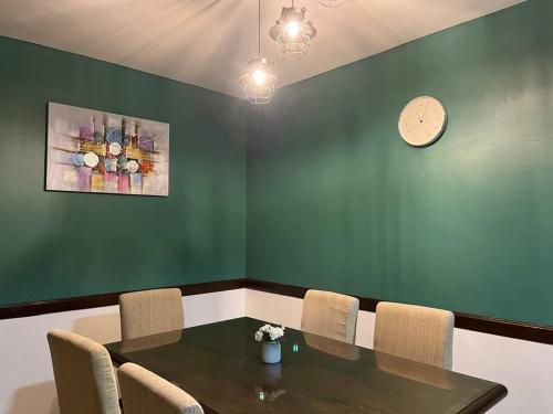 a dining room with a table and chairs and a clock at Sunset Greens Haven in Alor Gajah