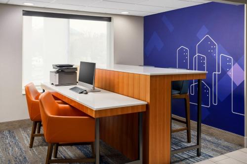 an office with a desk with a computer and orange chairs at Holiday Inn Express Irondequoit by IHG in Rochester