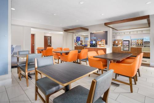 a dining room with tables and orange chairs at Holiday Inn Express Irondequoit by IHG in Rochester