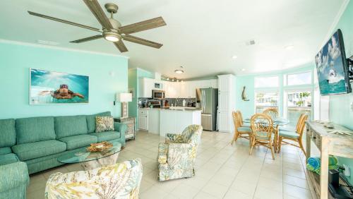 a living room with a green couch and a kitchen at Turtle Cove Views by Last Key Realty in Cudjoe Key