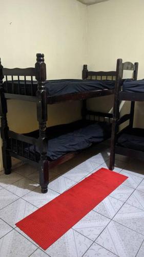 two bunk beds in a room with a red rug at Casa alojamento em Jandira in Jandira