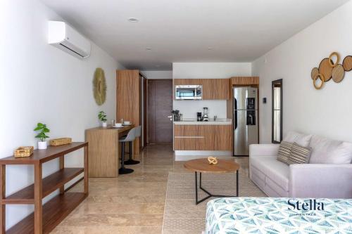 Una sala de estar con un sofá y una cocina. en Chic Studio at My Menesse In Playa with Roof Pool, en Playa del Carmen