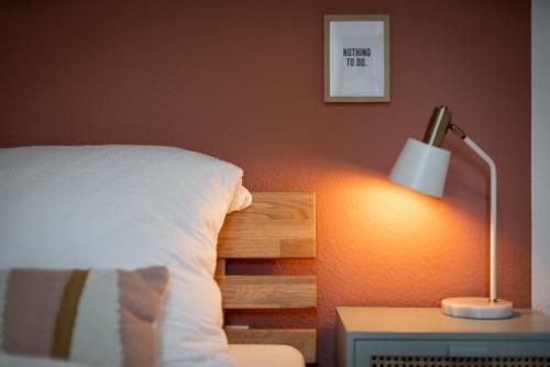 a bed with a white pillow and a lamp on a night stand at Flamingo - Zentral, Parken, Terrasse, PS4 in Frankenberg