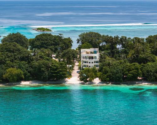 an island in the ocean with a building on the shore at Isla Retreat in Fehendhoo
