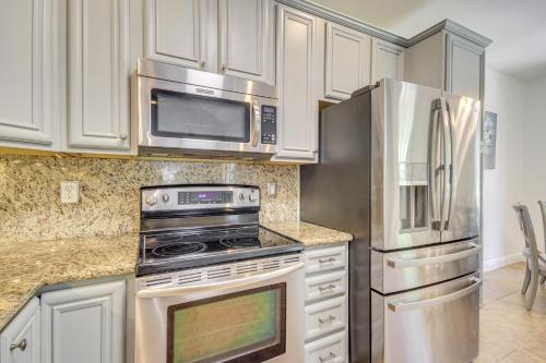 a kitchen with white cabinets and stainless steel appliances at Less Than 1 Mi to Beach - Home with Deck and Yard in Waveland! in Waveland