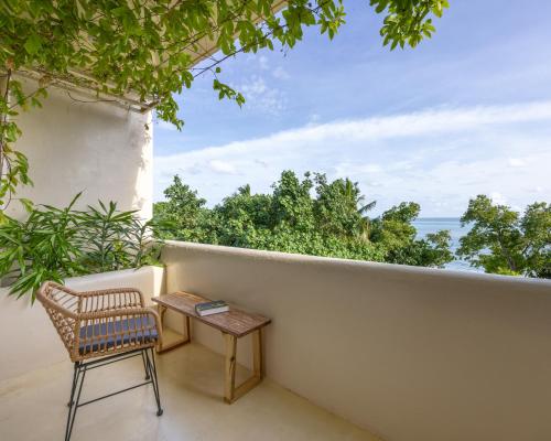 a table and chair on a balcony with a view of the ocean at Isla Retreat in Fehendhoo