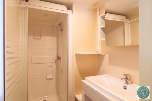 une salle de bain avec douche et lavabo dans l'établissement Mobil-home nature et détente, à Bias