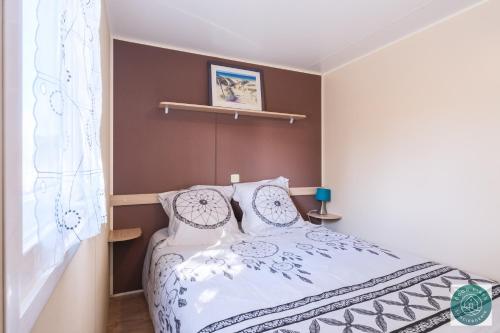 - une chambre avec un lit blanc et des oreillers dans l'établissement Mobil-home nature et détente, à Bias