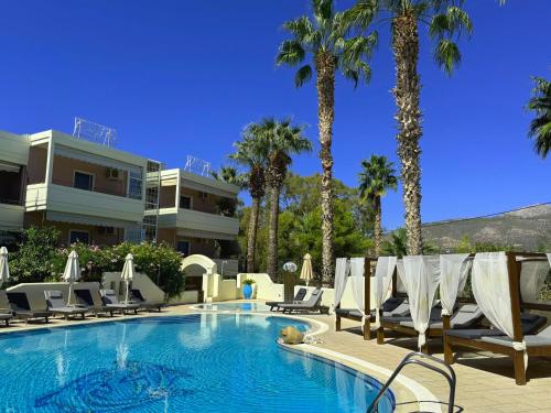 エレトリアにあるSun Rise Hotel Apartmentsのヤシの木が茂るスイミングプール(長椅子付)
