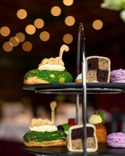 a three tiered plate of food with dinosaur cakes and pastries at Bunchrew House Hotel in Inverness